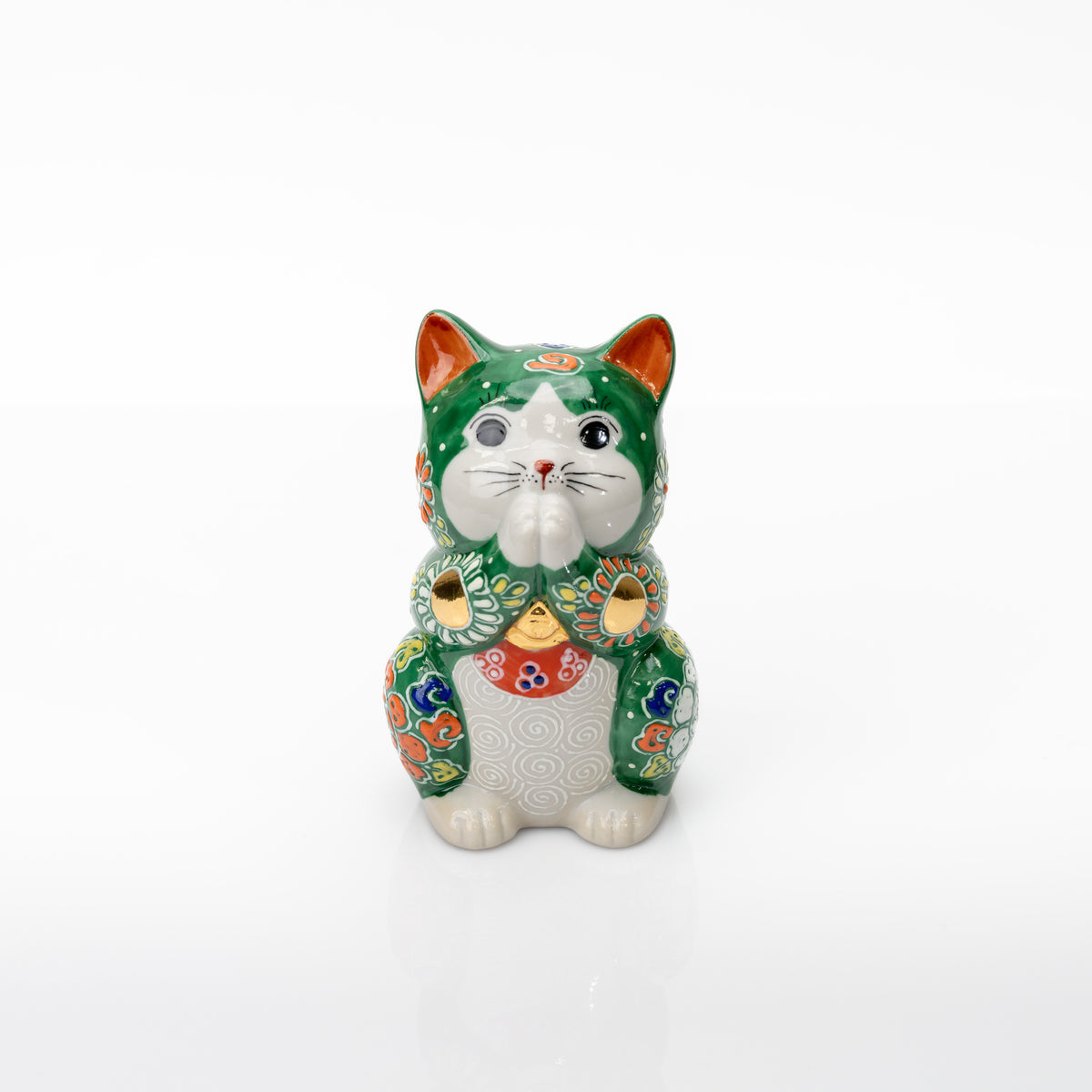 Front view of a green Kutani praying cat with joined white paws, raised floral patterns, and gold-colored accents.