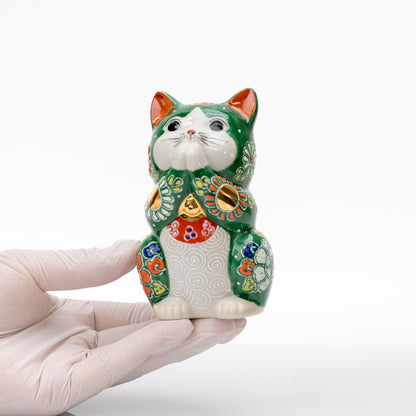 Green Kutani praying cat held in a gloved hand to show its compact size.