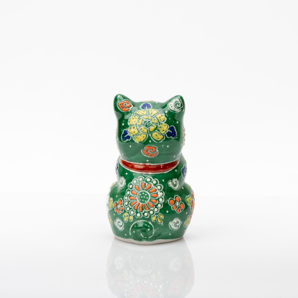 Back of the green praying cat showing yellow and orange flowers, white dots, a red collar, and a curled tail.