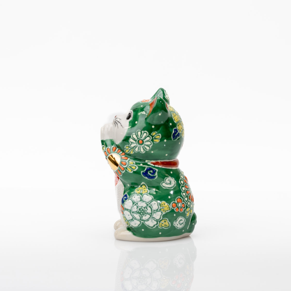 Side view of the green porcelain cat showing a white flower on its body and yellow floral decoration on the head.