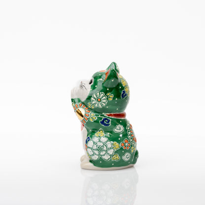 Side view of the green porcelain cat showing a white flower on its body and yellow floral decoration on the head.
