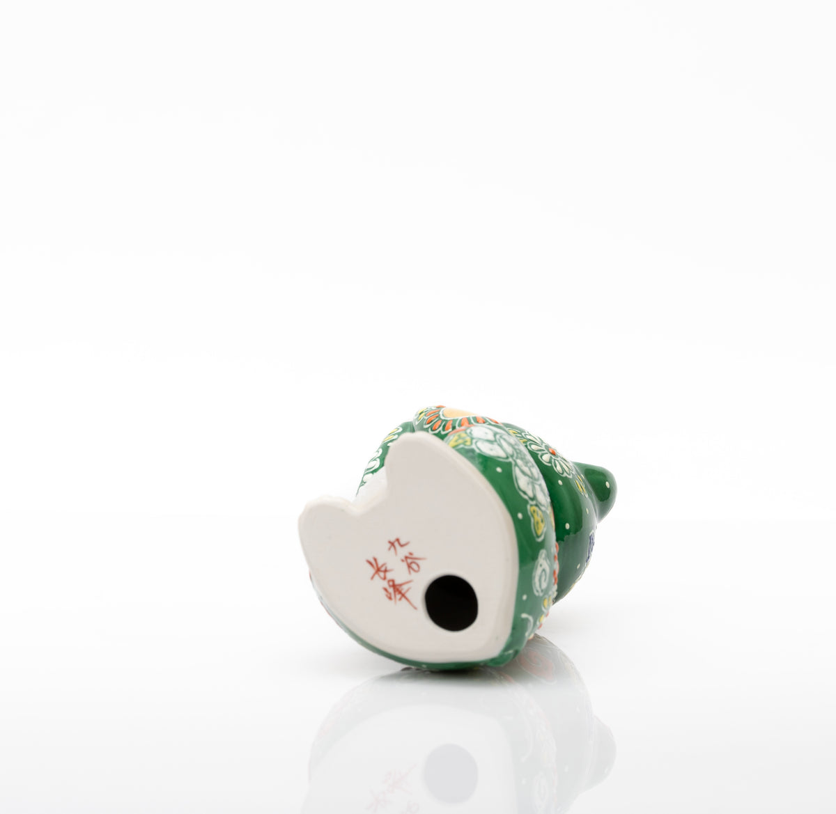Underside of the green porcelain cat showing a red 九谷 長峰 mark and a round opening.