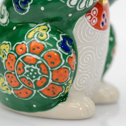 Close-up of an orange flower with raised white outlines beside the cat’s spiral-patterned belly.