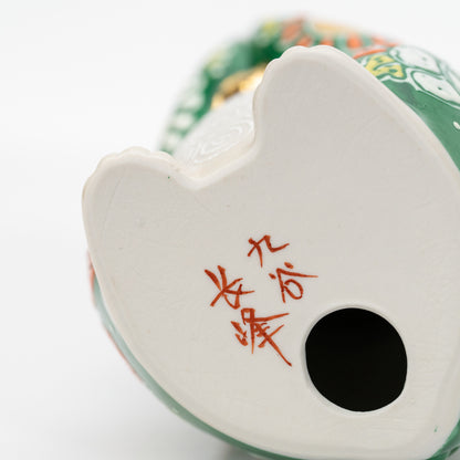 Close-up of the red 九谷 長峰 mark and round opening on the white porcelain base.