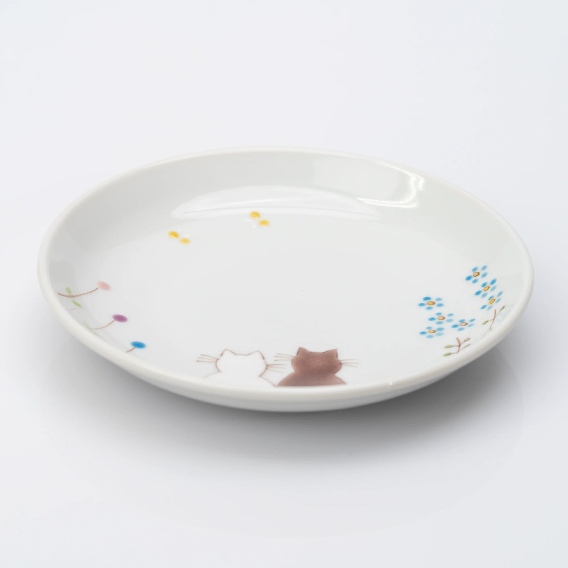 Angled view of white Kutani plate with two cats and delicate flowers