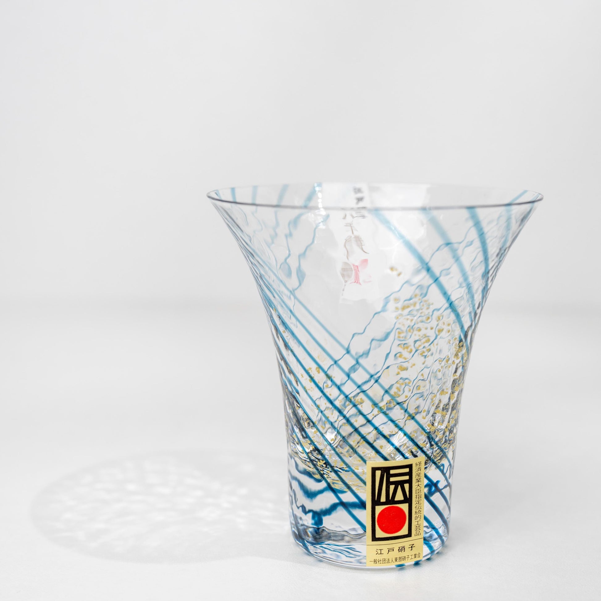 Angled view of blue crystal sake cup with gold pattern