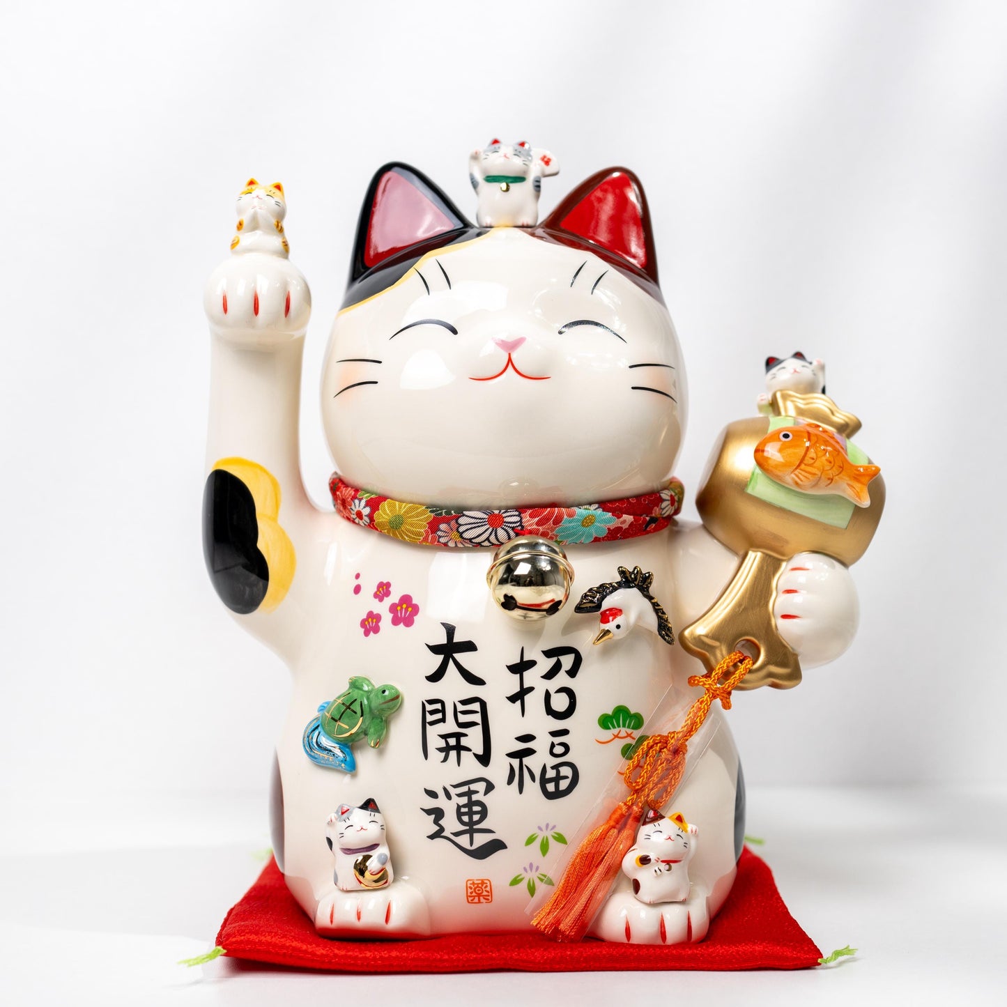 Large maneki neko figurine by Yakushi Kiln on red cushion