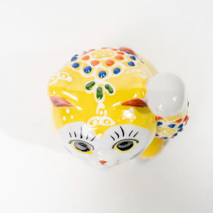Close-up of painted detail on yellow lucky cat figurine
