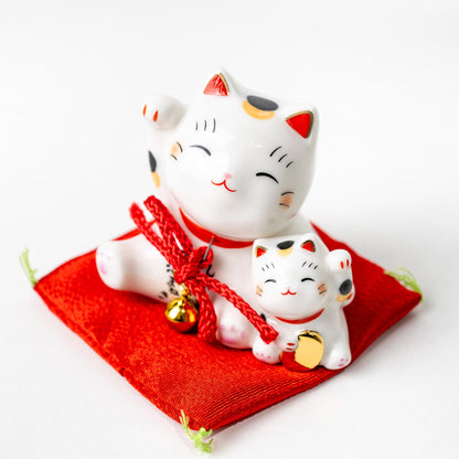 Angled view of mother and kitten Maneki Neko on red cushion