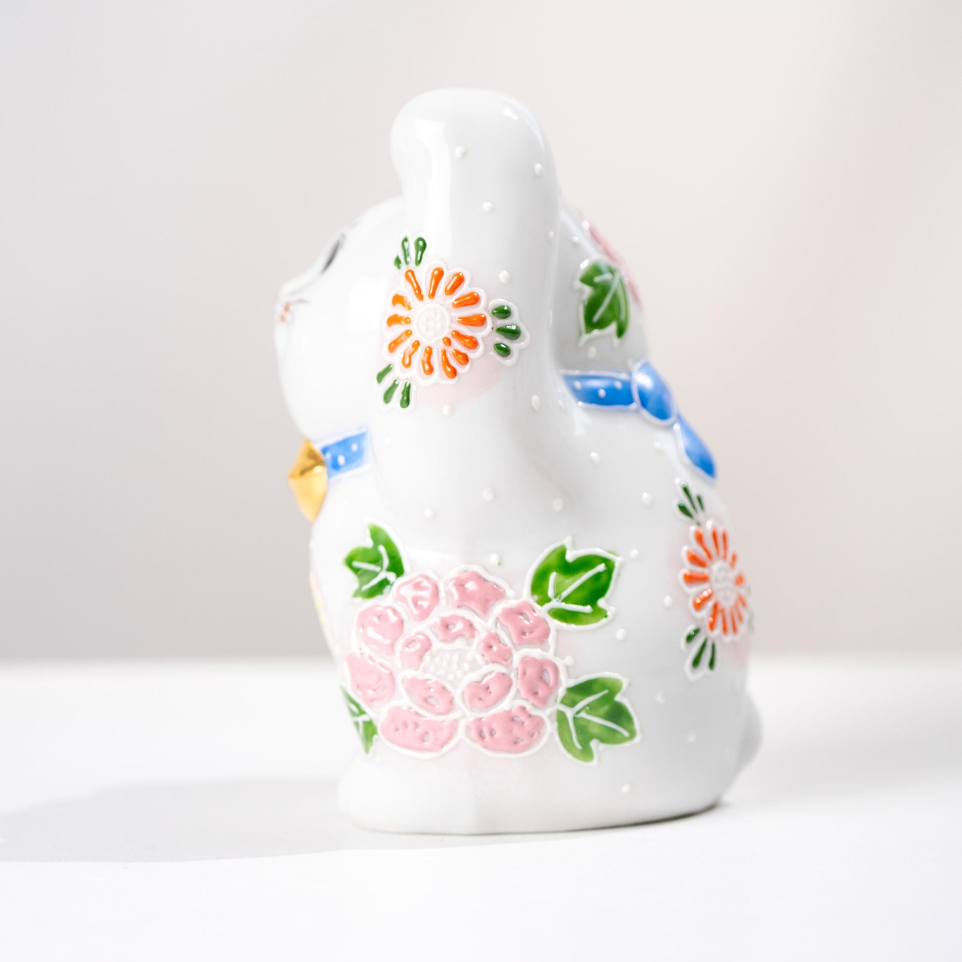 Back view of Kutani lucky cat showing painted floral detail