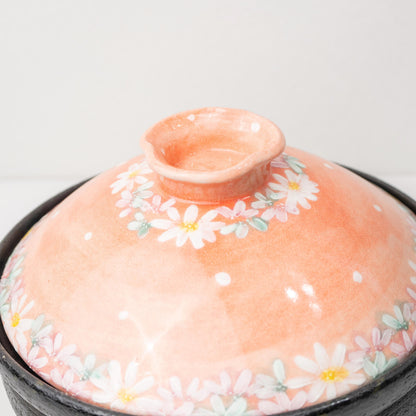 Angled close-up of the lid handle on a pink floral donabe