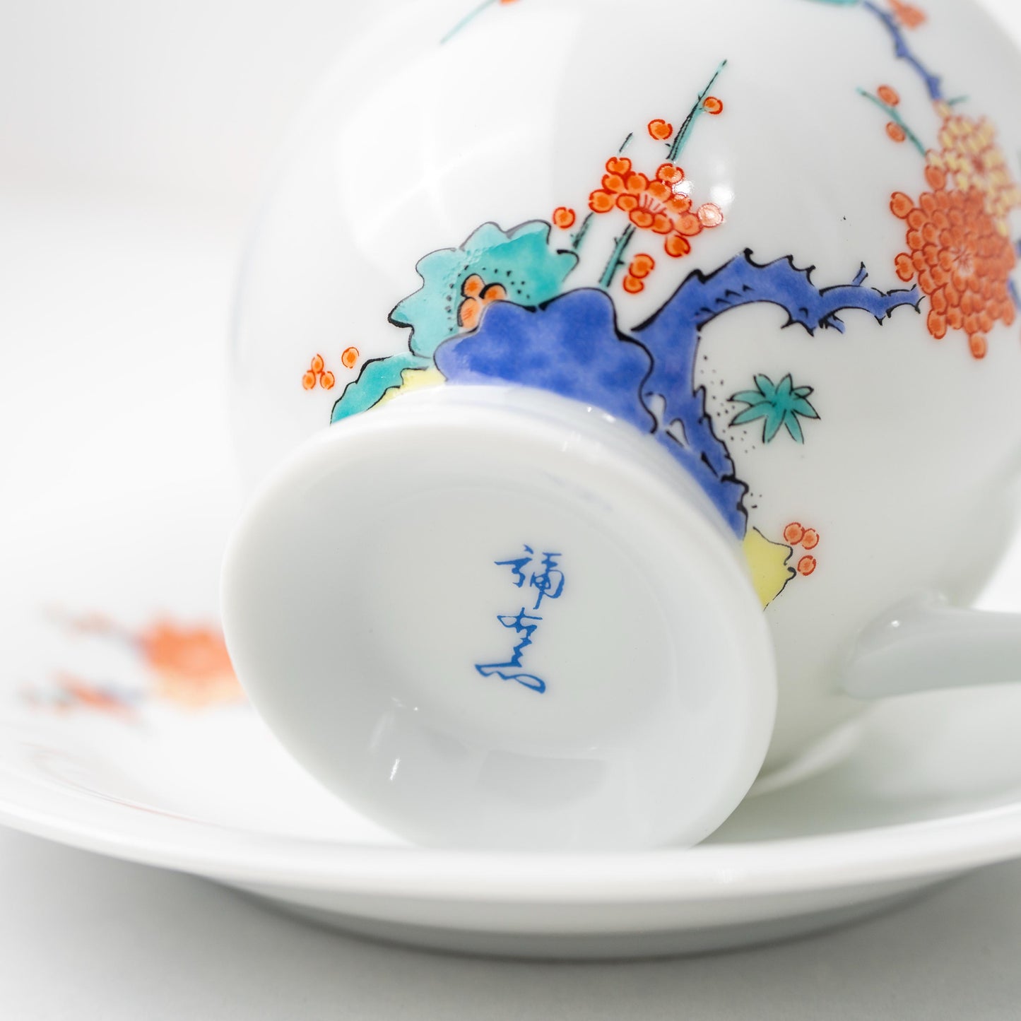 Angled view of Arita bird and plum blossom cup and saucer set
