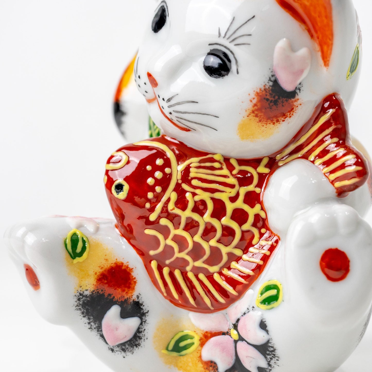 Side view of lucky cat figurine showing red sea bream motif