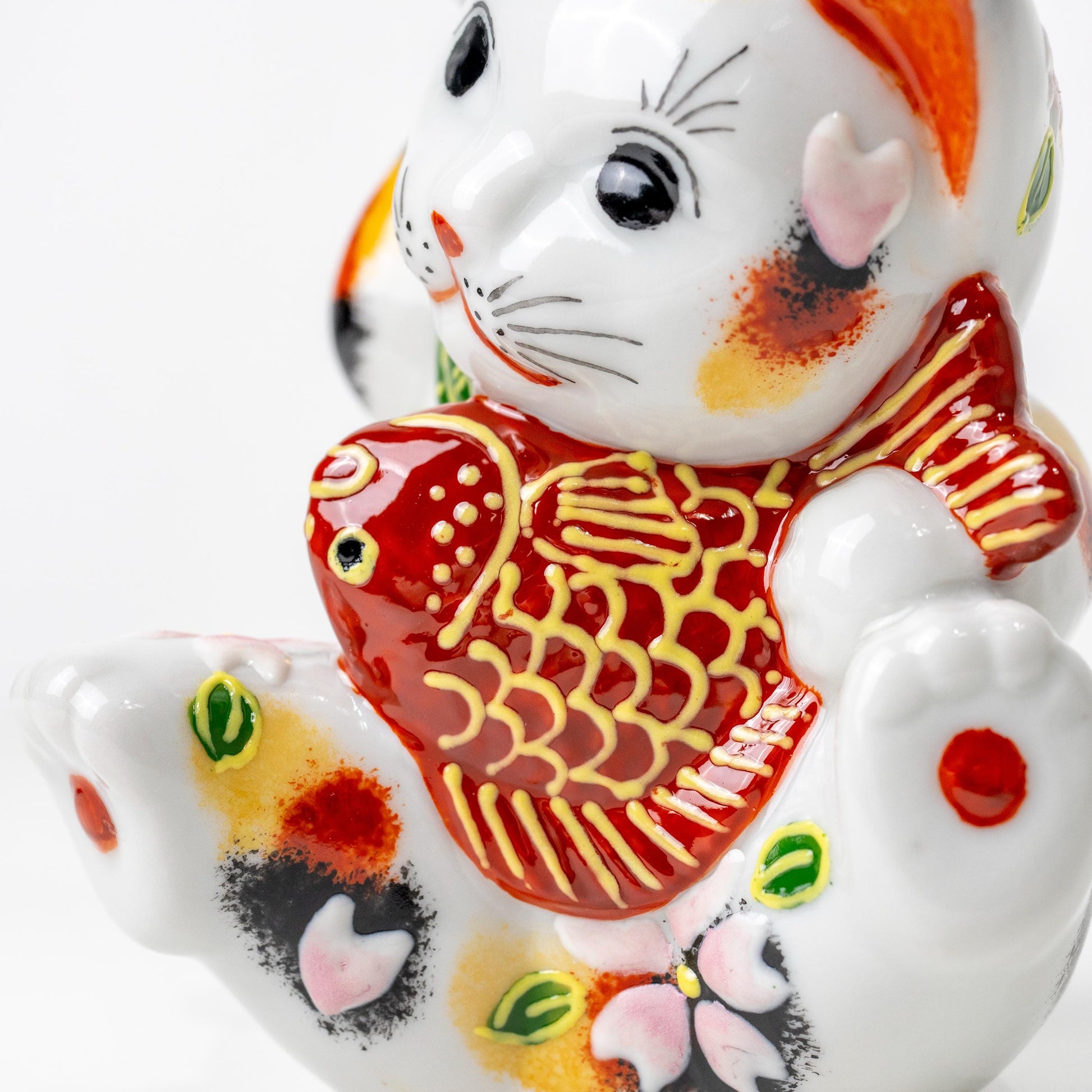 Side view of lucky cat figurine showing red sea bream motif