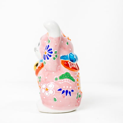Angled view of pink lucky cat statue in porcelain