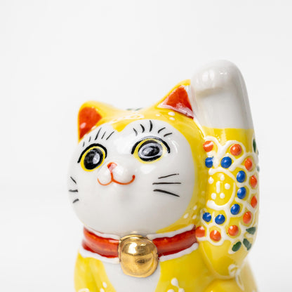 Three-quarter view of small yellow lucky cat statue