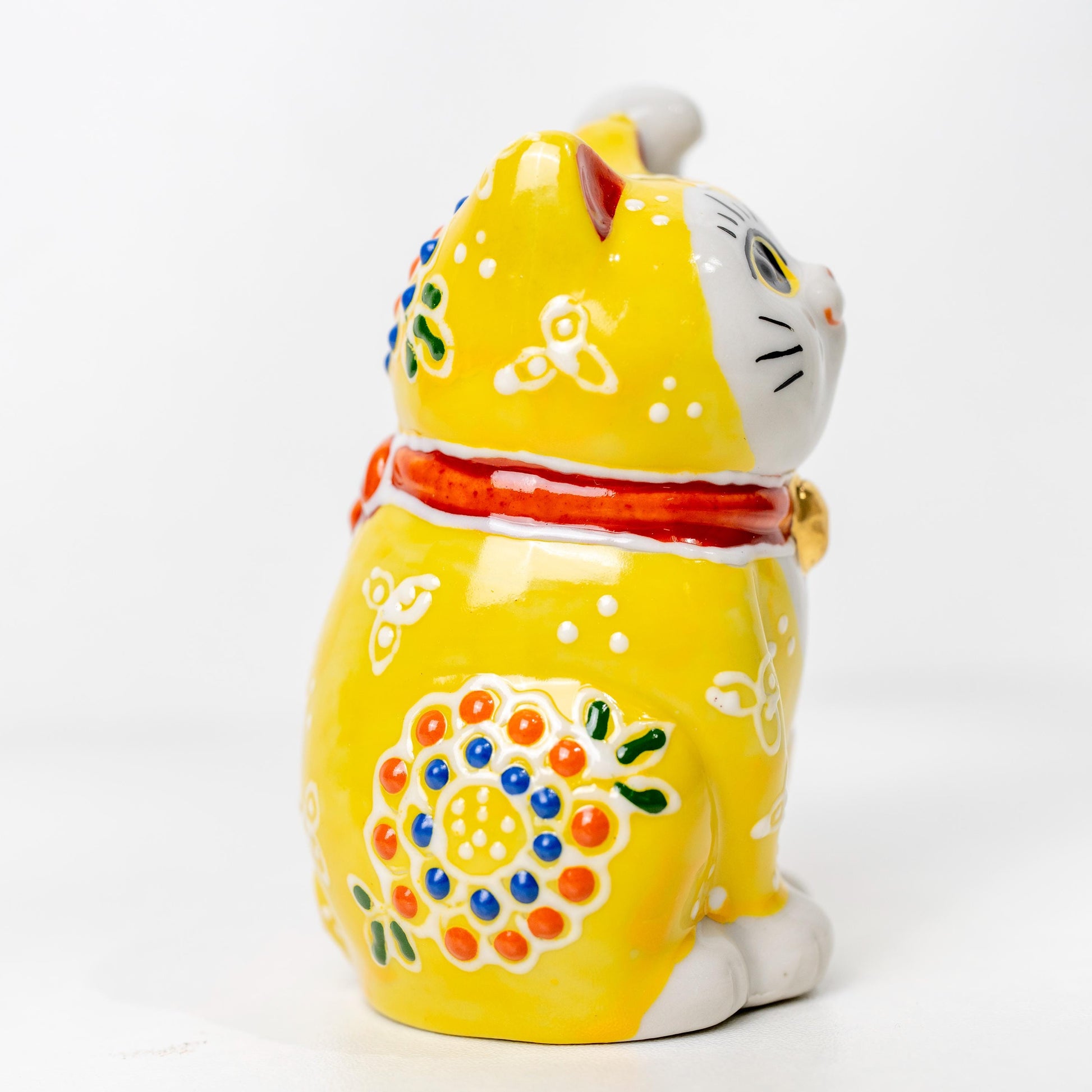 Side view of Kutani lucky cat with raised paw