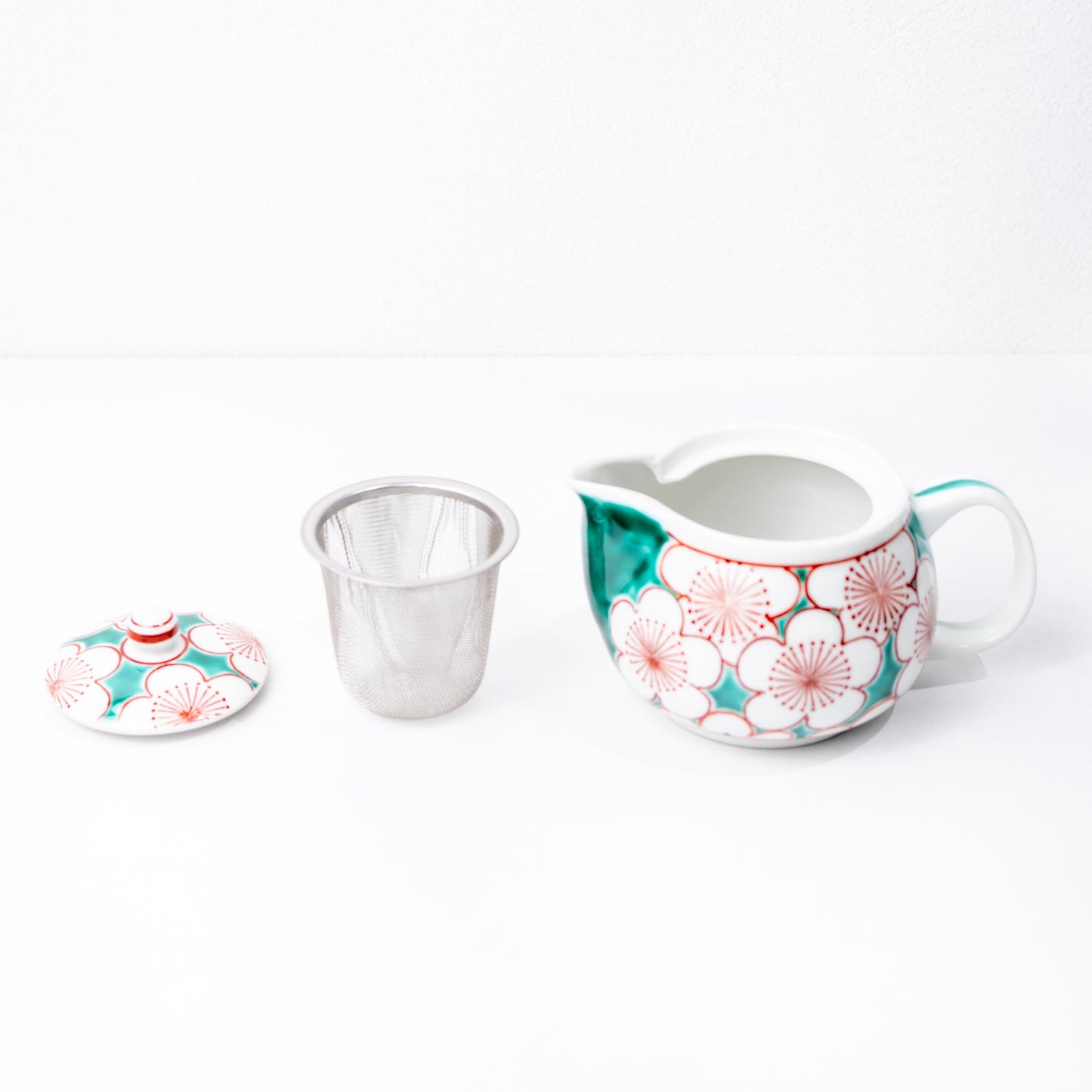 Angled view of teapot and two yunomi cups in red and blue kutani pattern