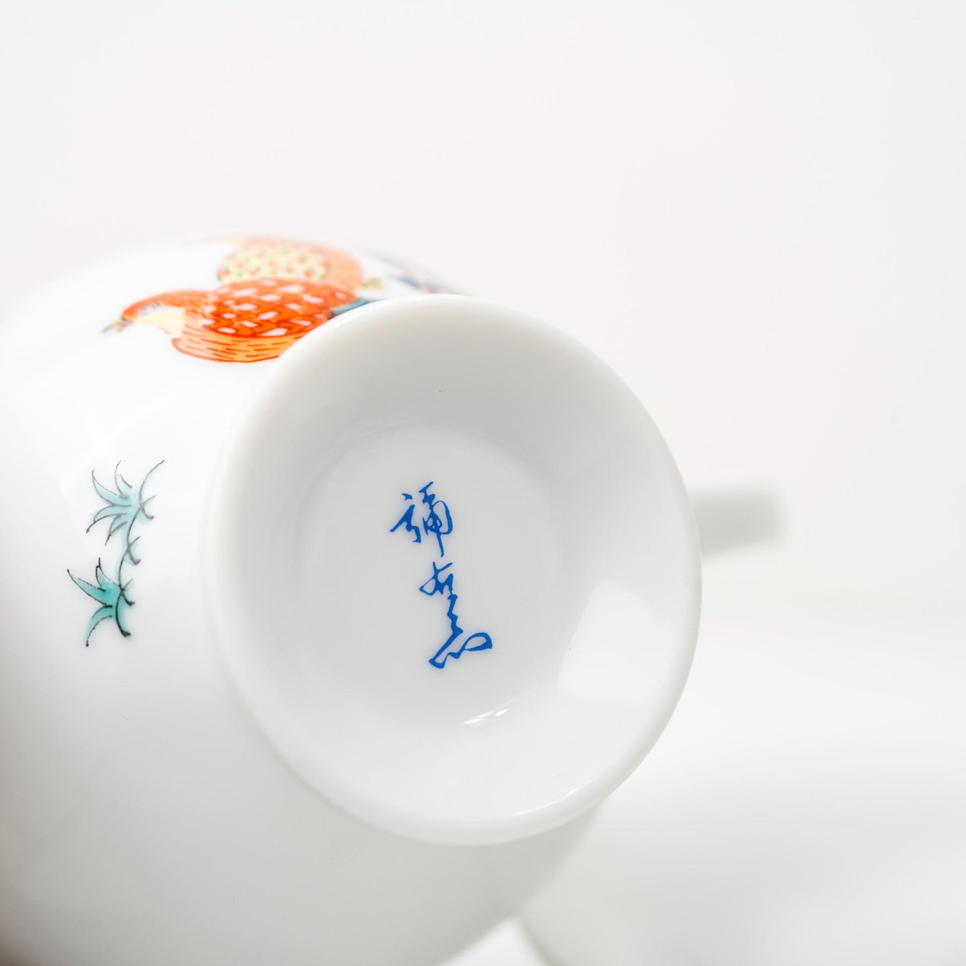 Angled view of hand-painted Arita cup and saucer with quail motif