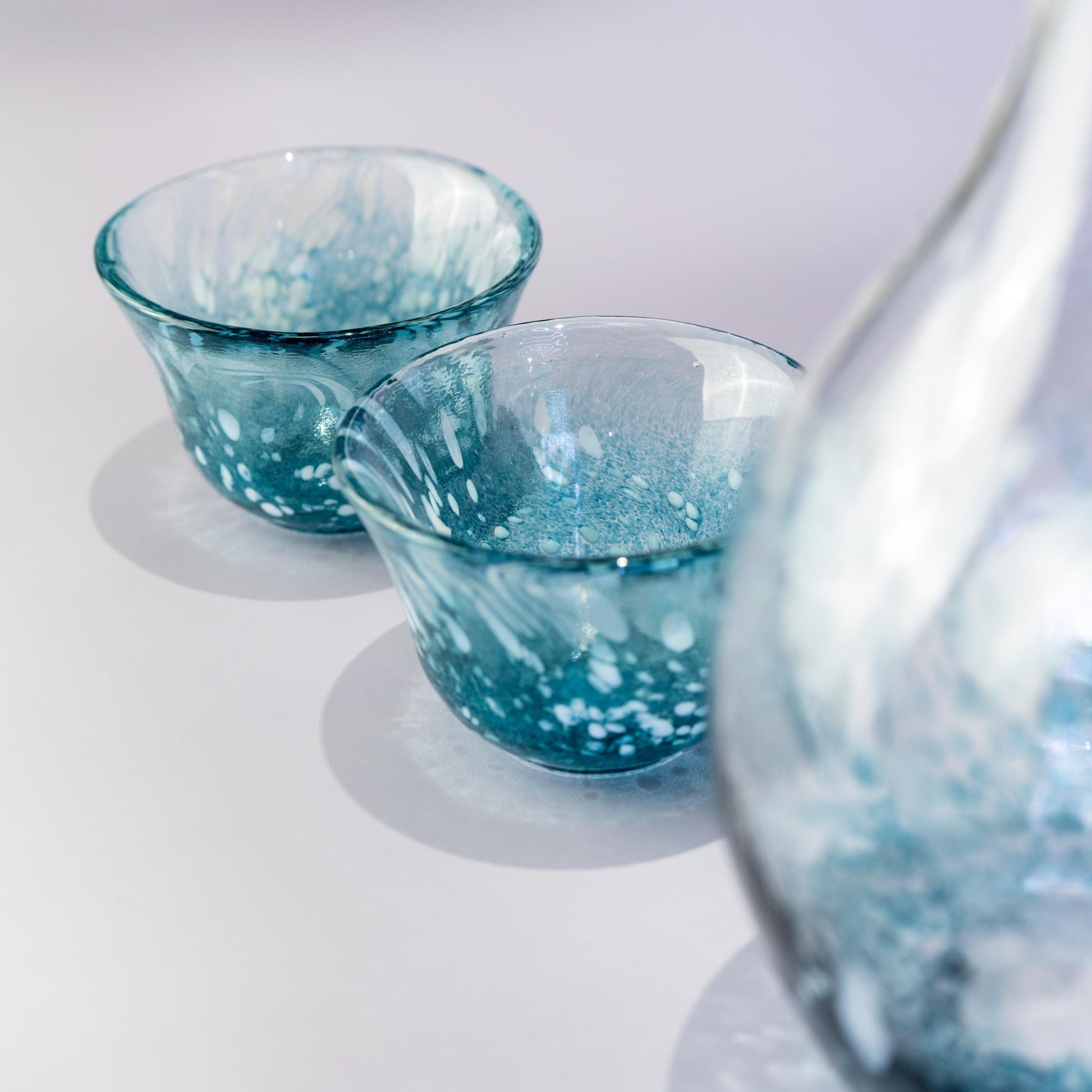Top angle of sake cup and carafe in blue glass set