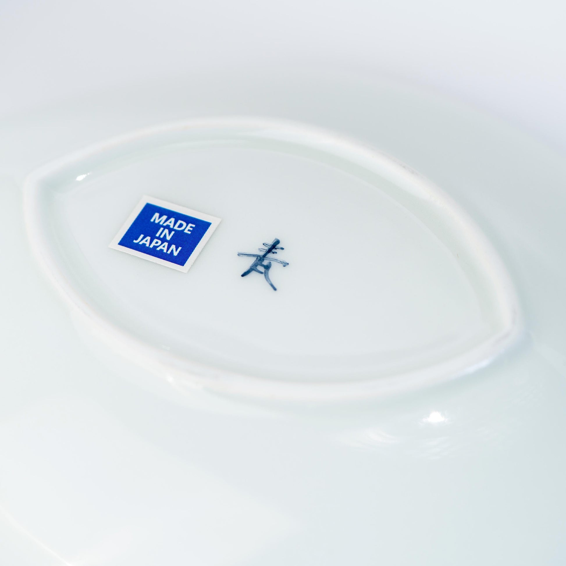 Underside of porcelain leaf plate showing base and sticker