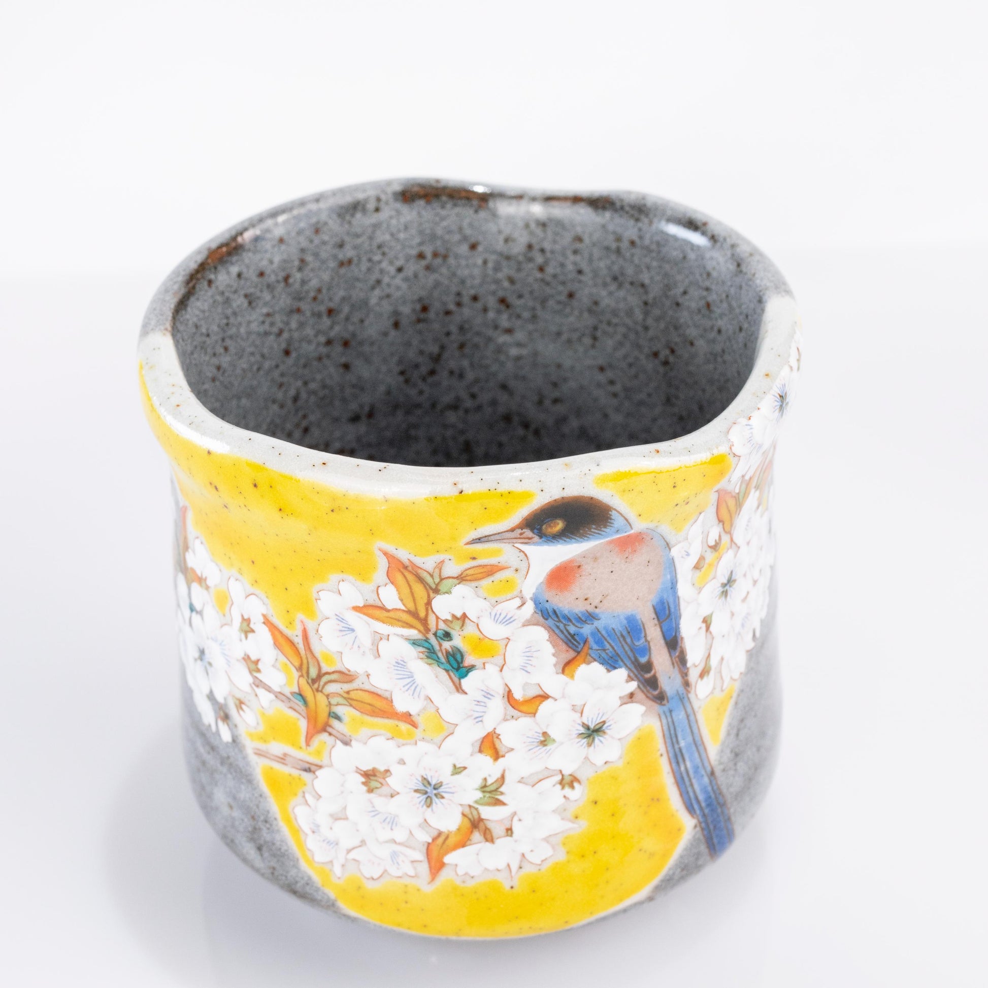 Angled view of Yoshidaya style tea cup with sakura and bird design
