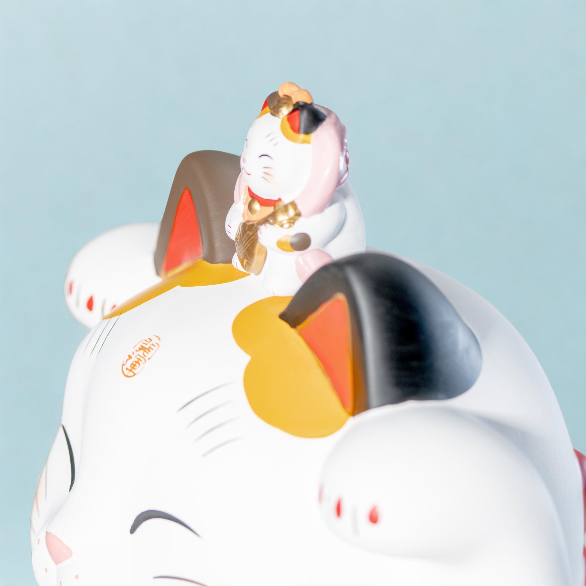 Side view of left paw lucky cat statue in ceramic