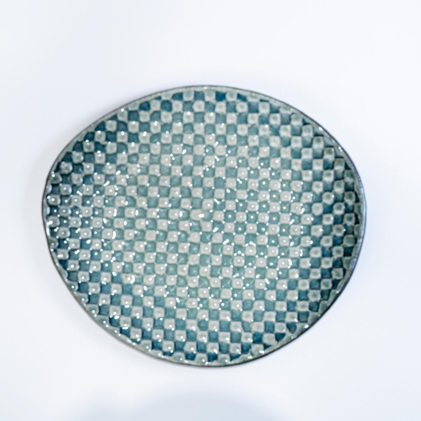 Close-up of saucer surface in olive green mosaic glaze