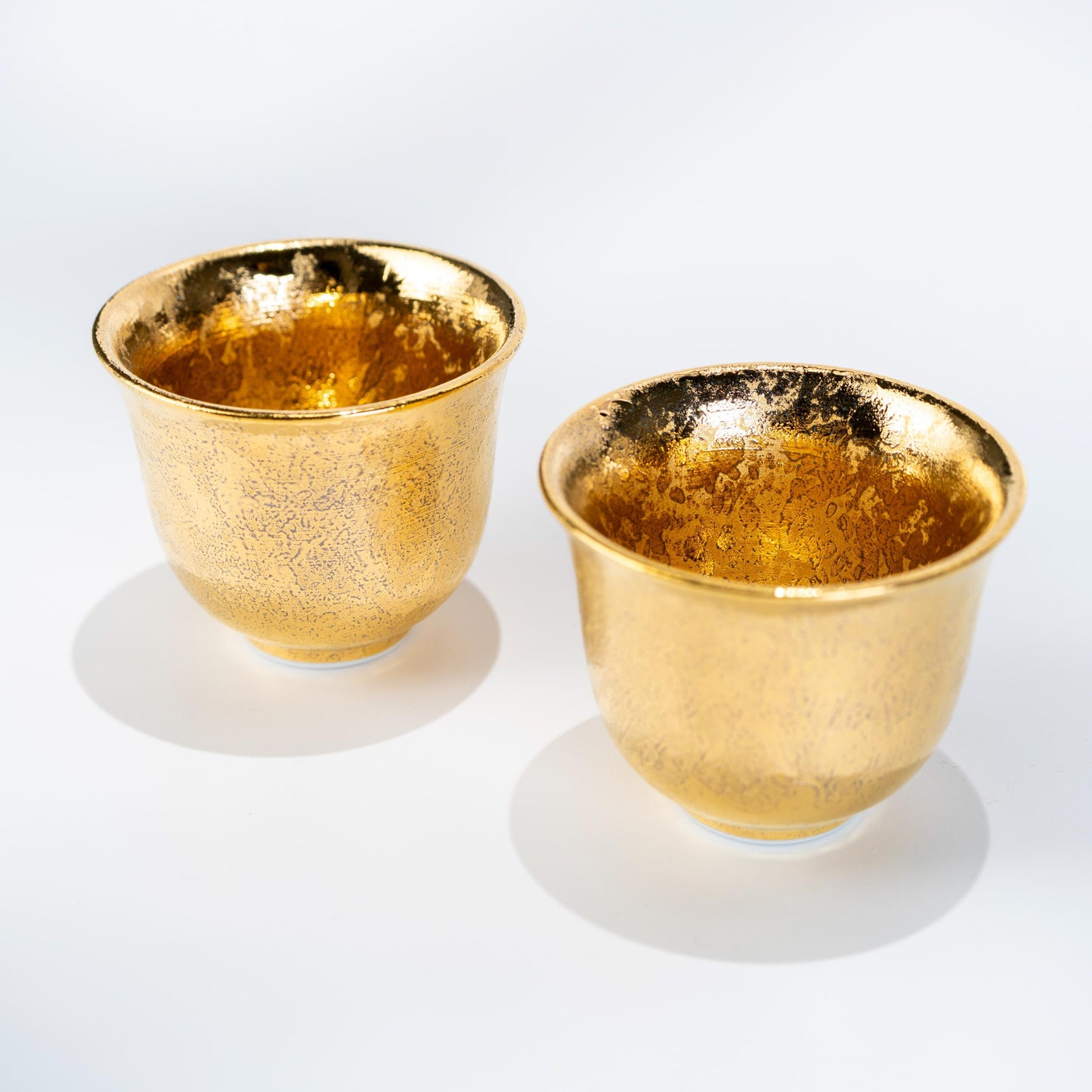 Angled view of gold glazed Arita teapot and cups on white background