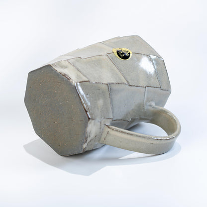 Back side of greige stoneware mug with faceted texture