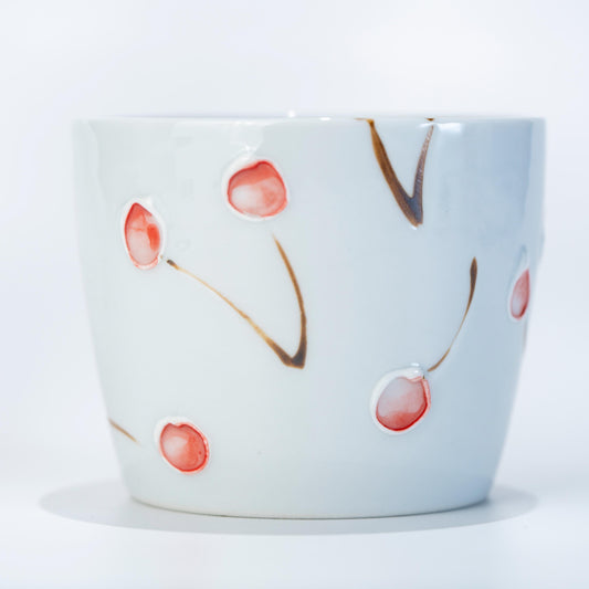 Angled view of Arita Hasami cherry yunomi cup in white porcelain