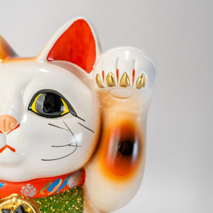 Close-up of Tokoname white lucky cat statue with raised paw and face detail