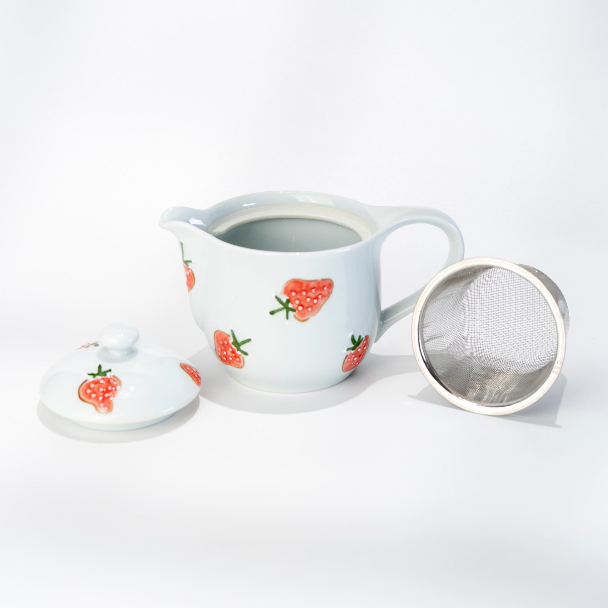 Angled view of Arita strawberry teapot with built-in strainer