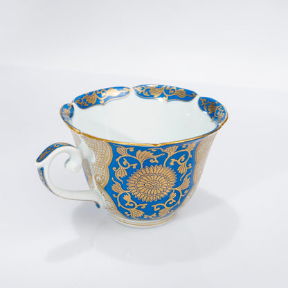 Front view of blue and gold Arita cup and saucer on white background