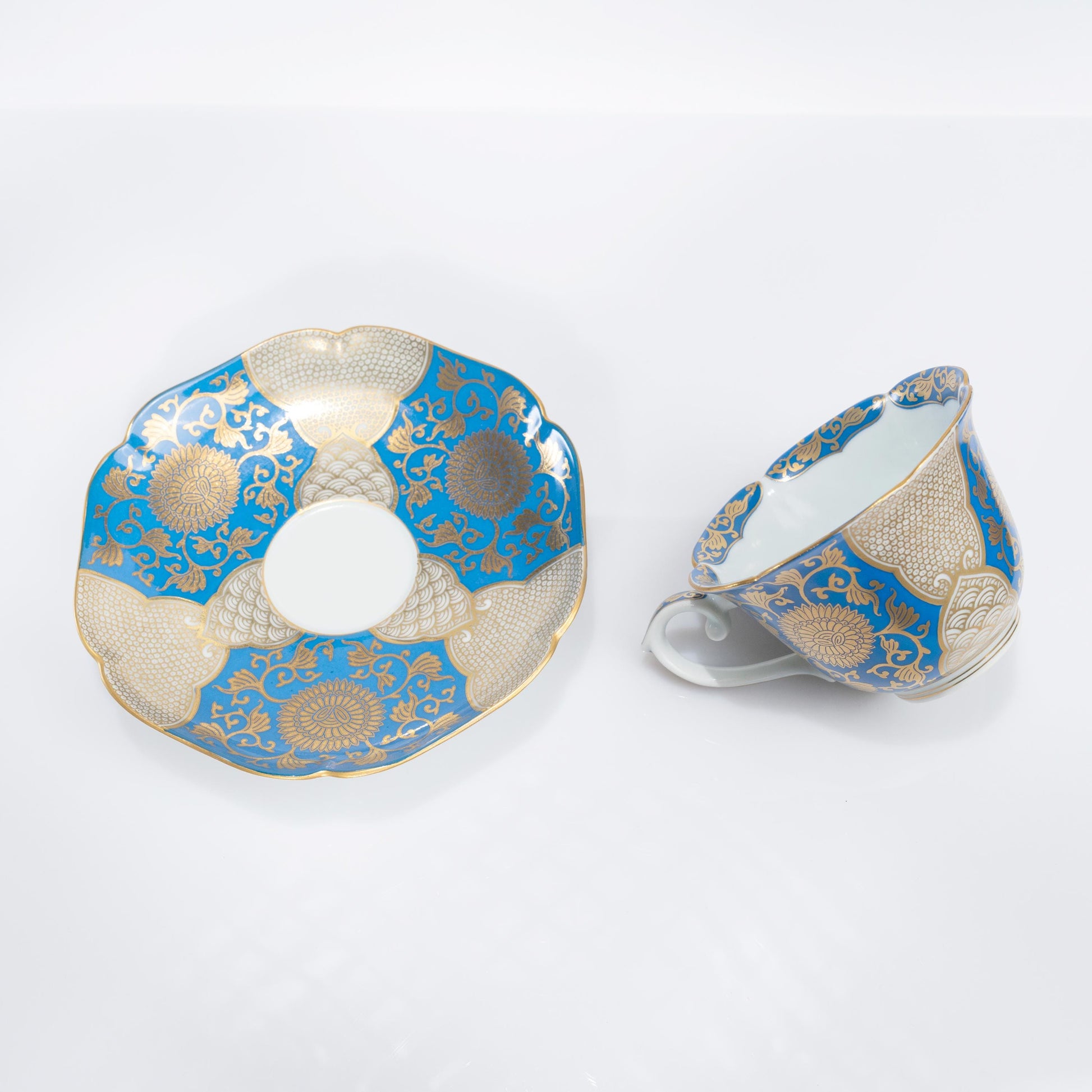 Angled view of hand-painted blue and gold coffee cup and saucer set