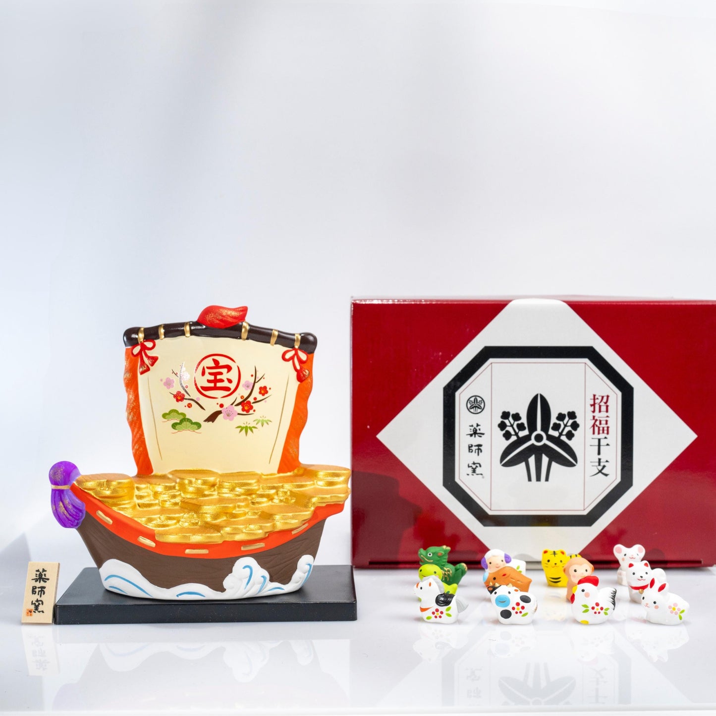 Front view of ceramic zodiac treasure boat display on black base