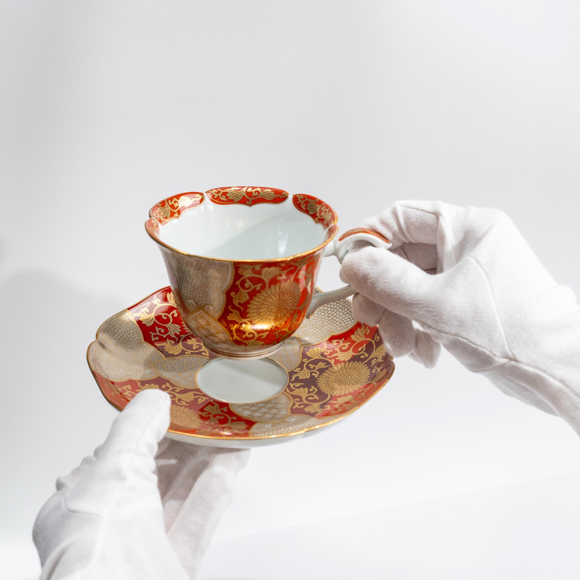 Angled view of hand-painted red gold porcelain cup and saucer