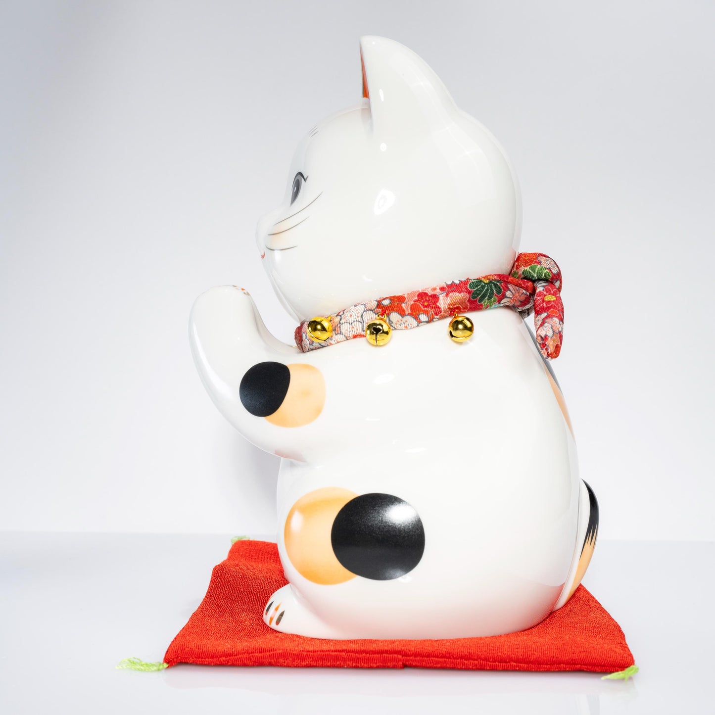 Front angle of large ceramic lucky cat on red base