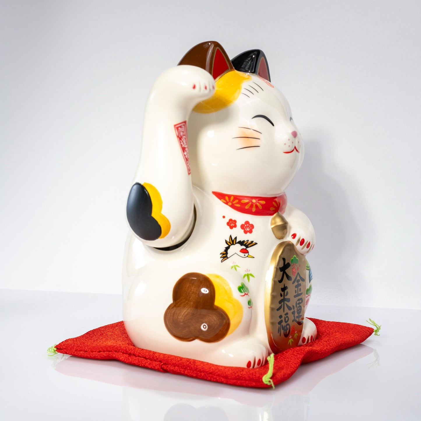 Side view of electric beckoning cat on red base
