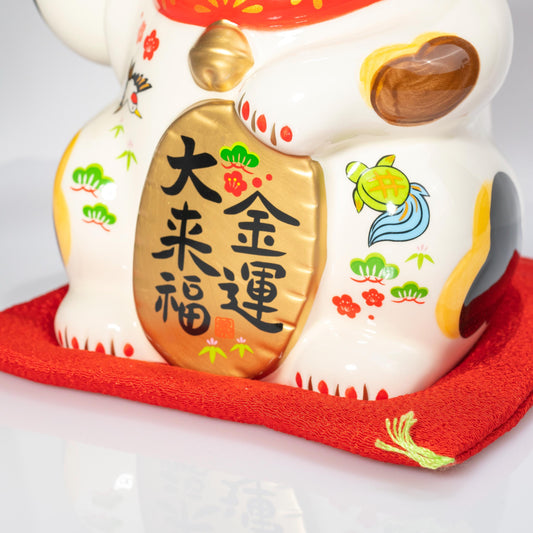 Front close-up of lucky cat holding fortune plaque