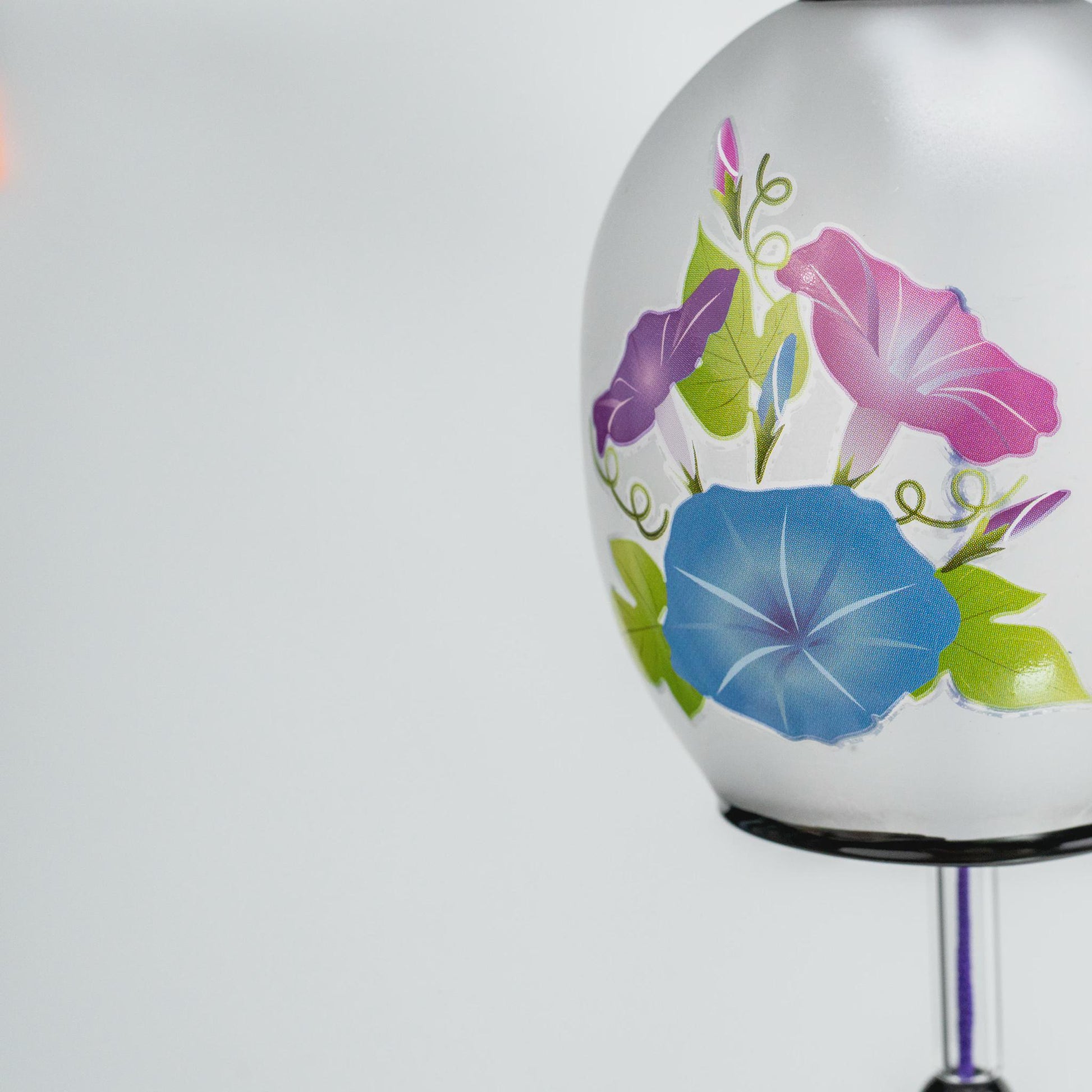 Purple paper tanzaku printed with a flowing-water wave pattern below the glass furin