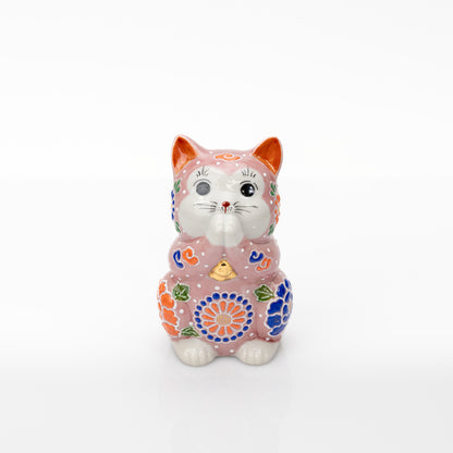 Front view of a pink Kutani praying cat with joined paws, orange and blue flowers, and white dot decoration.