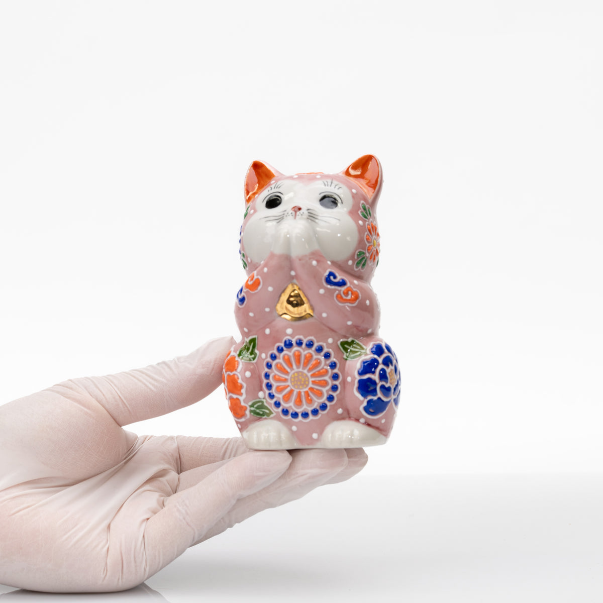 Pink Kutani praying cat held in a gloved hand to show its compact size.