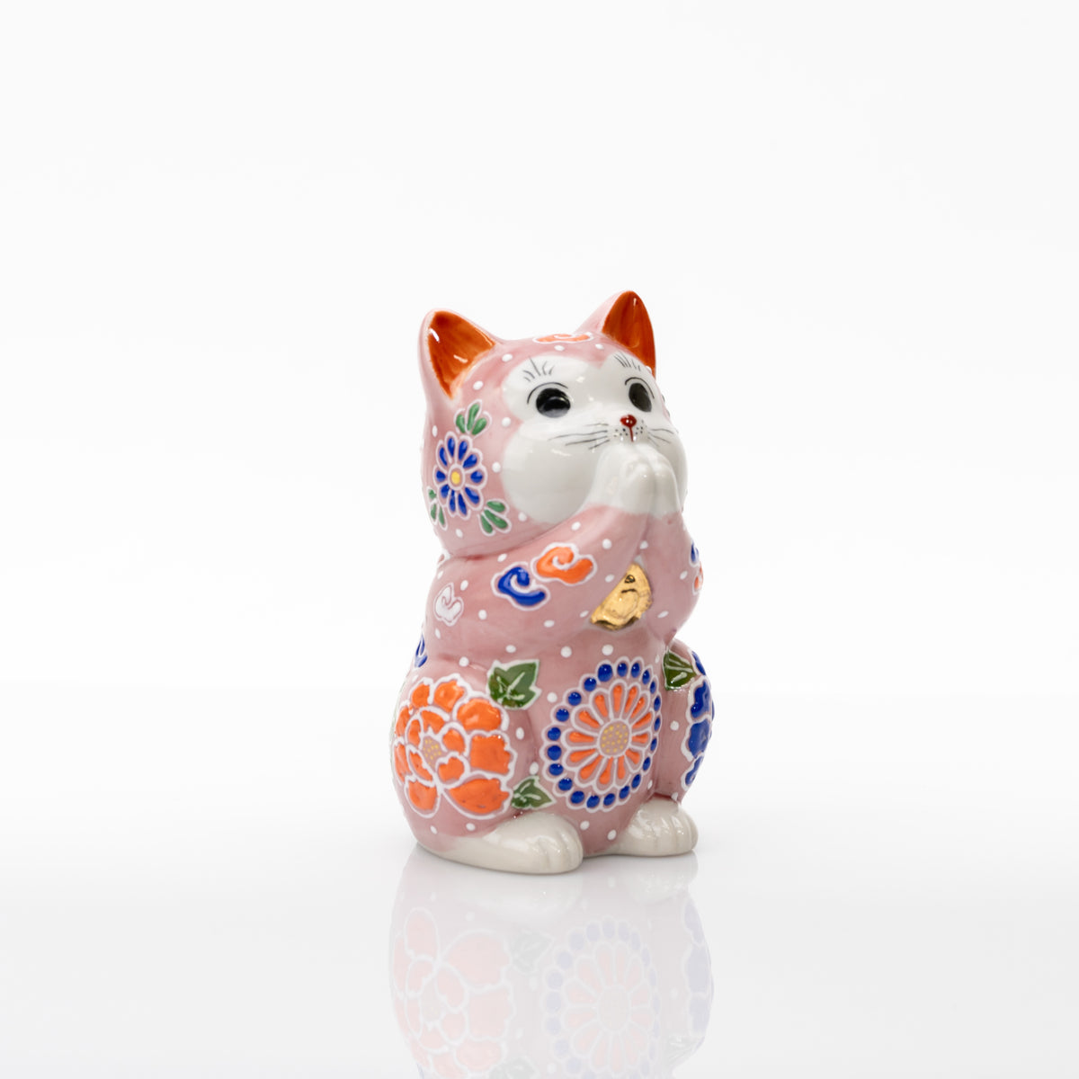 Three-quarter view of the pink praying cat showing orange floral decoration on the side.
