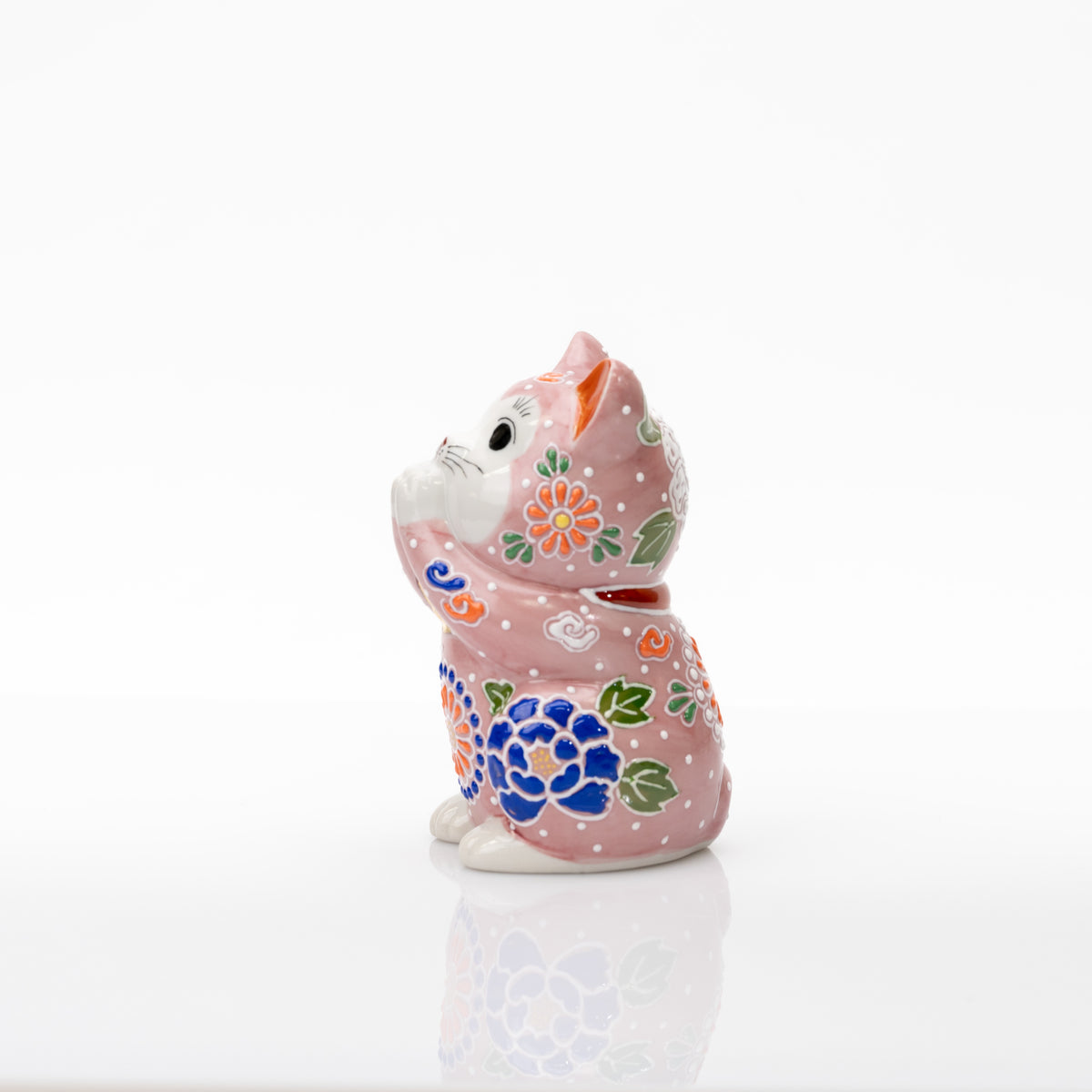 Opposite side of the pink praying cat showing a cobalt-blue flower and green leaves.
