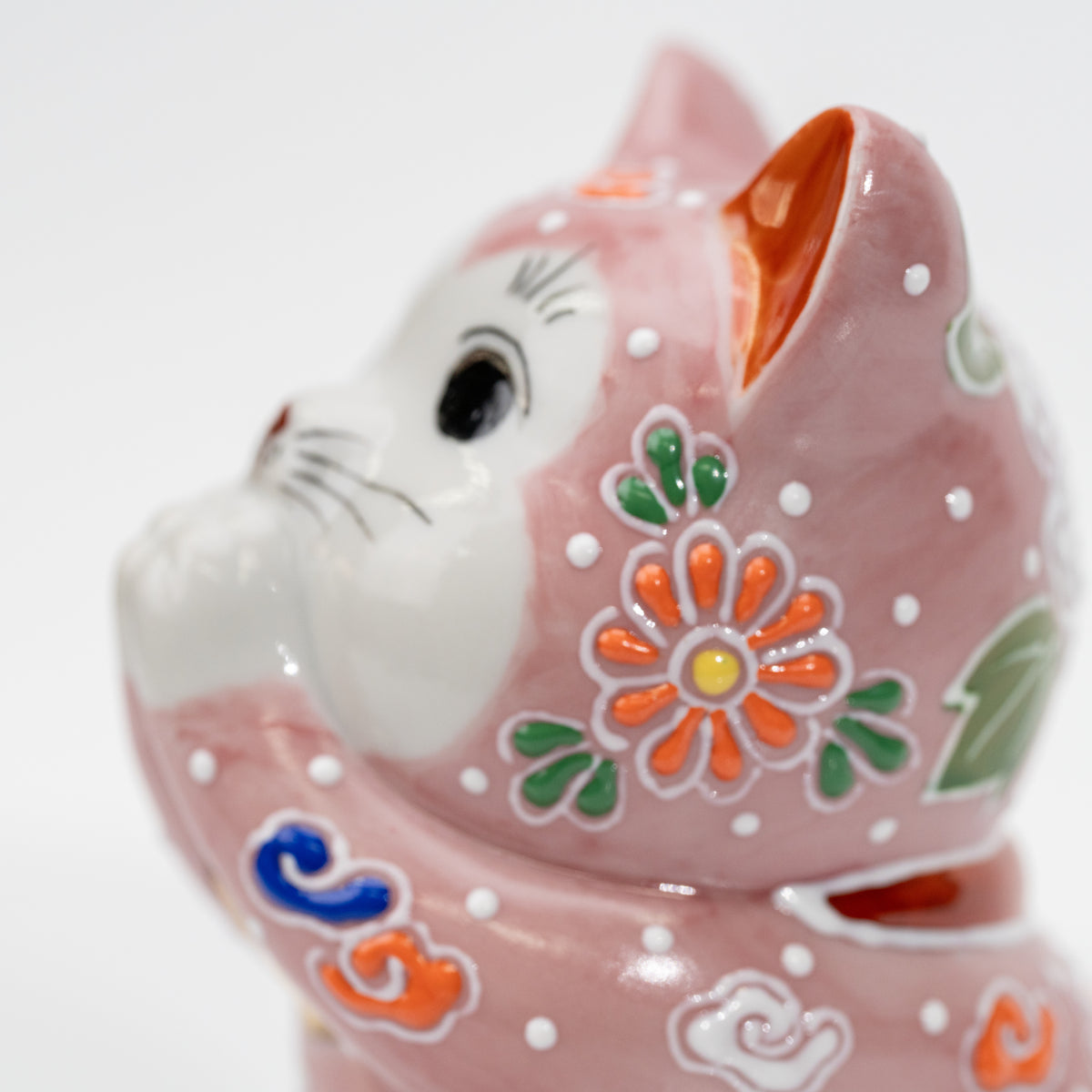 Close-up of an orange flower with raised white outlines on the pink cat’s cheek.
