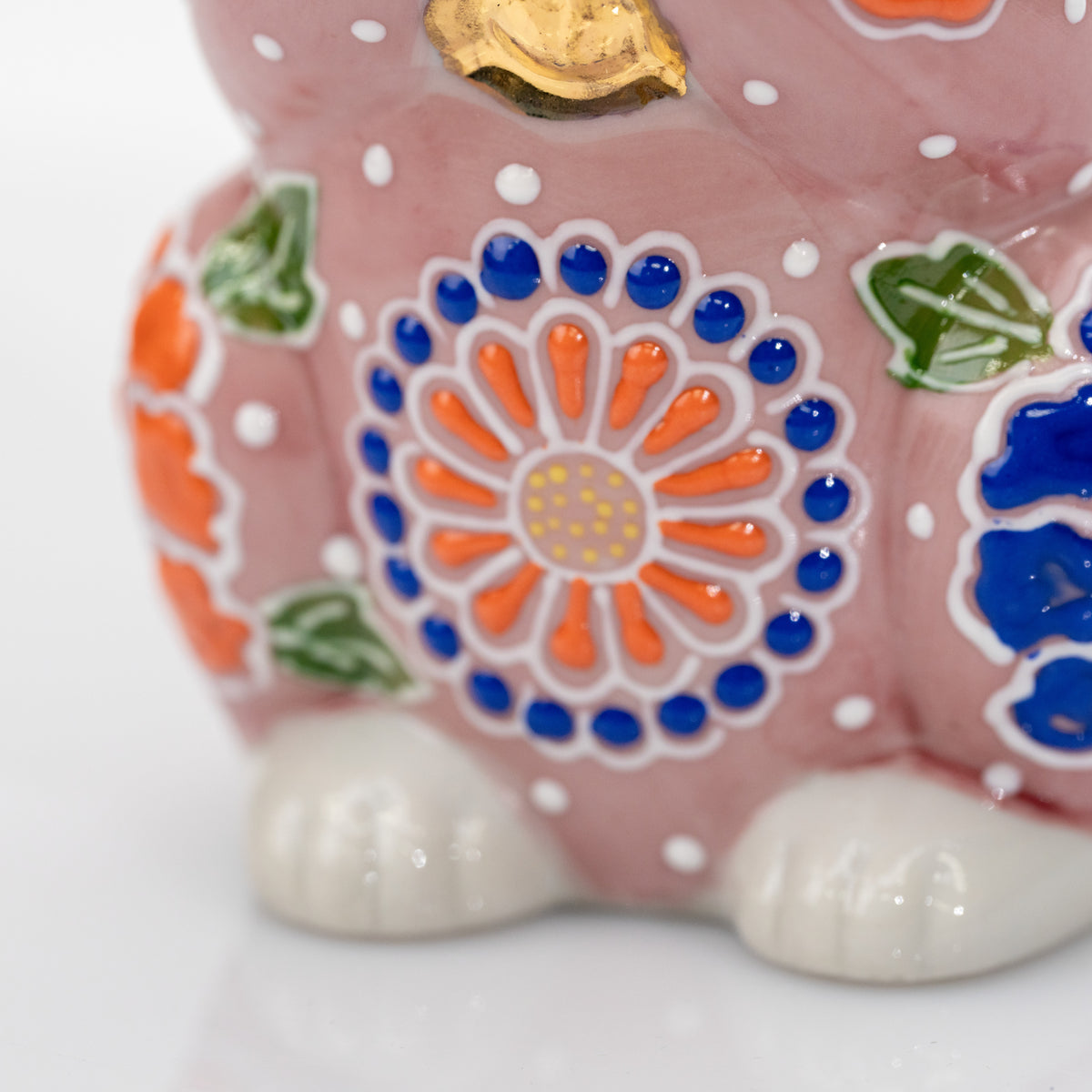 Close-up of the orange and cobalt-blue round flower on the front of the pink ceramic cat.