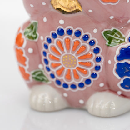 Close-up of the orange and cobalt-blue round flower on the front of the pink ceramic cat.