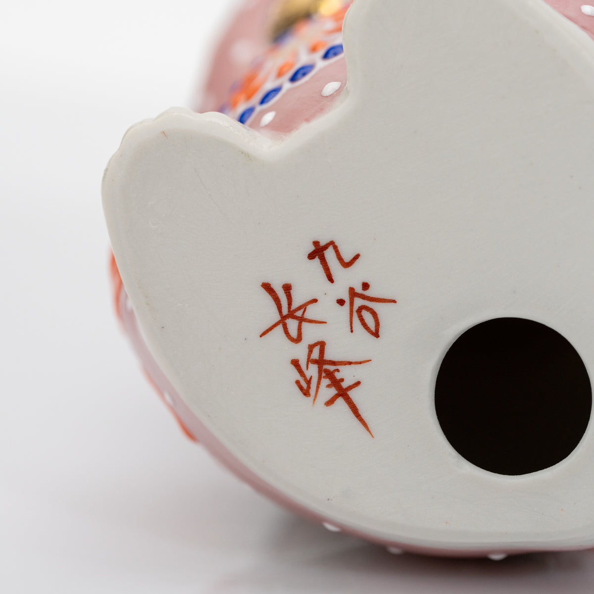 Close-up of the red 九谷 長峰 mark on the white ceramic base.