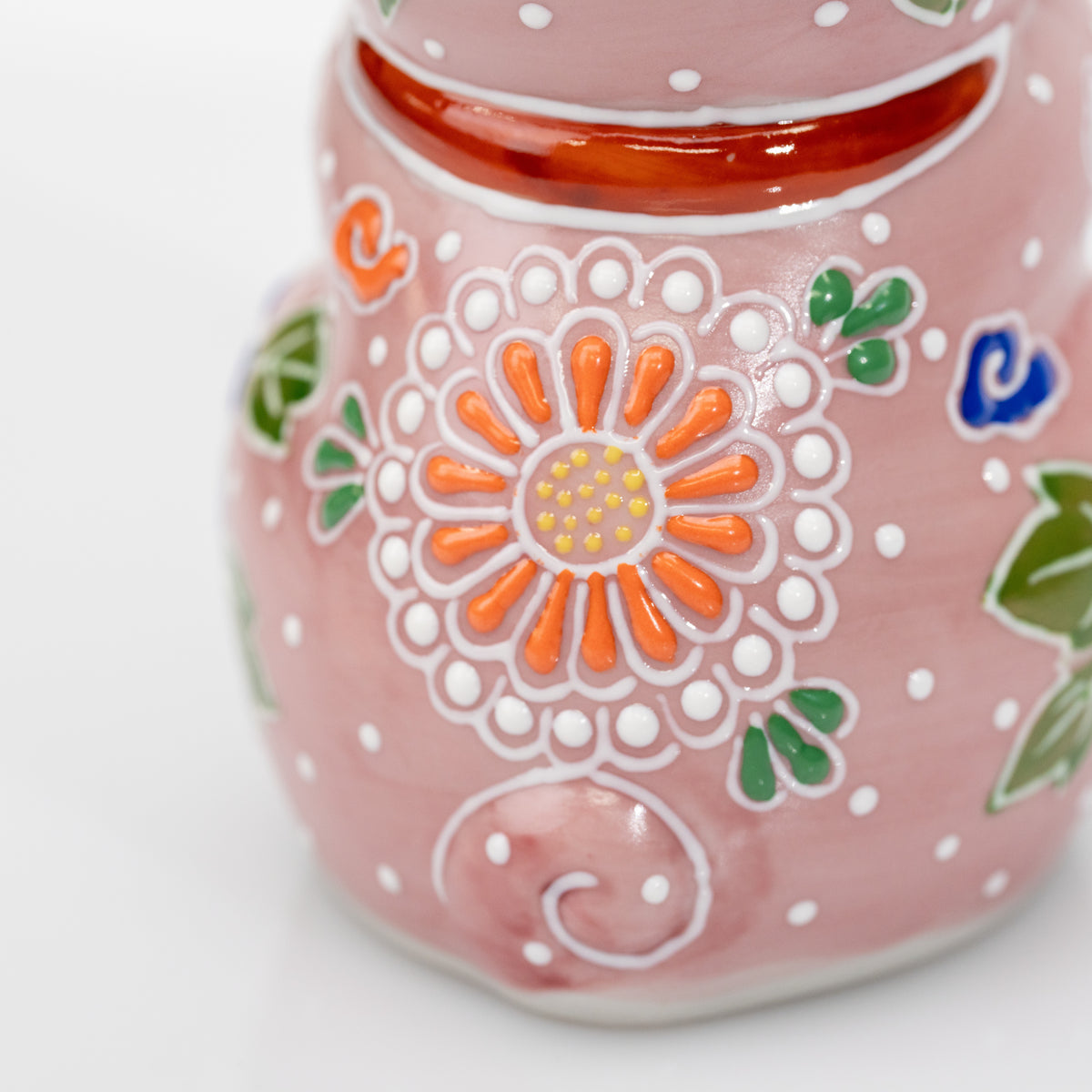 Close-up of the orange round flower and white dotted decoration on the back of the pink cat.